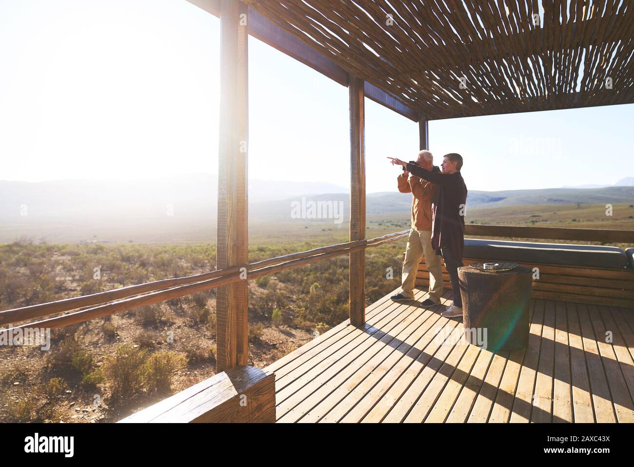 Senior couple looking at sunny view from safari lodge balcony Stock Photo