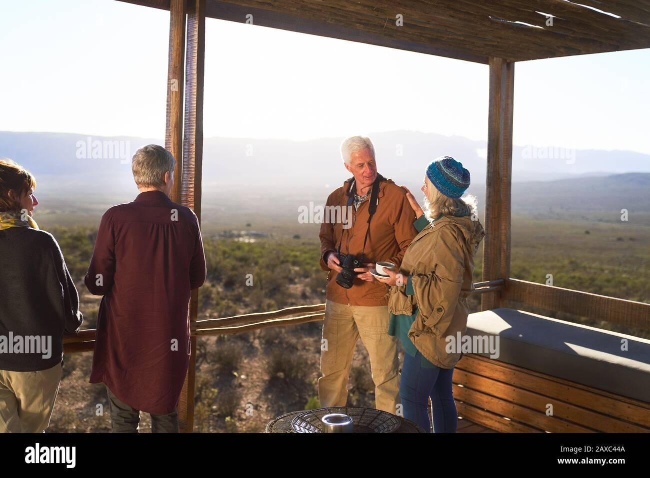 Senior couple with camera and tea on sunny safari lodge balcony Stock Photo