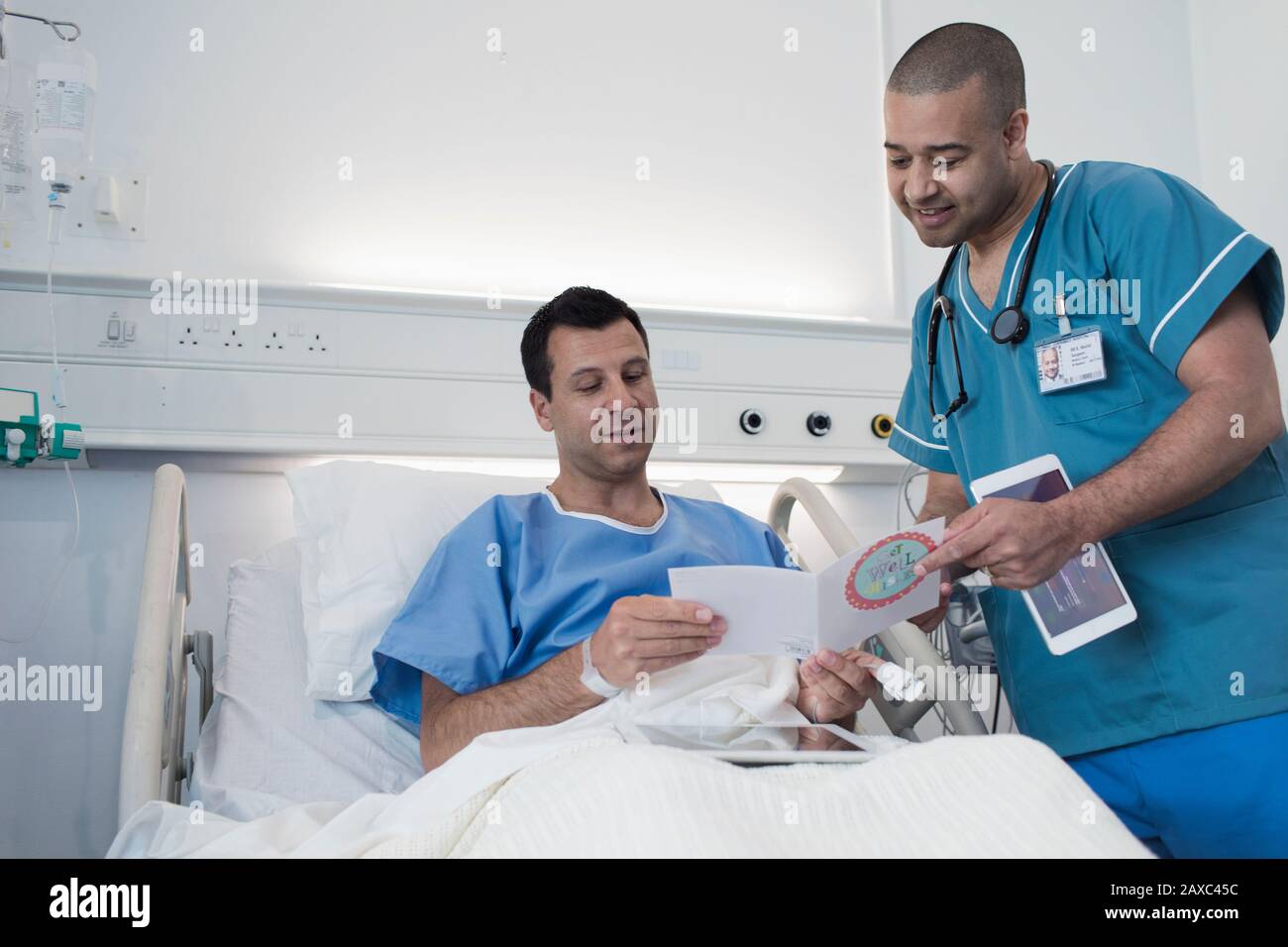 Male patient showing greeting card to nurse in hospital room Stock Photo