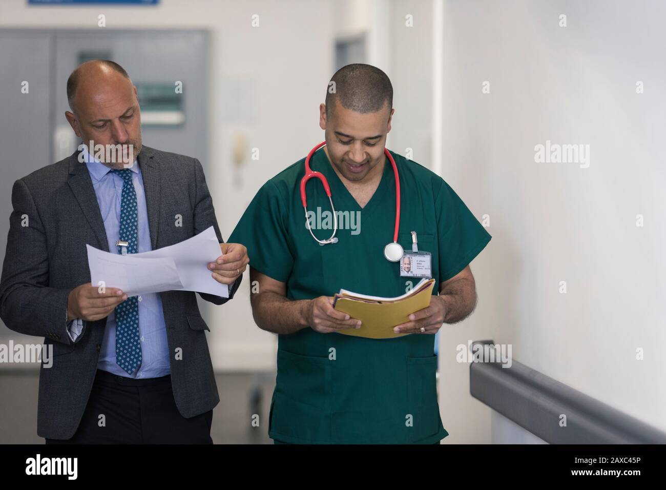 Male administrator and surgeon reading paperwork in hospital corridor Stock Photo