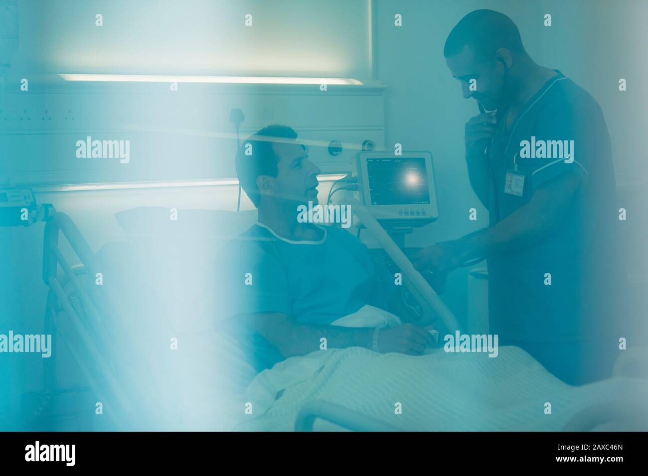 Male nurse with stethoscope examining patient in hospital bed Stock ...