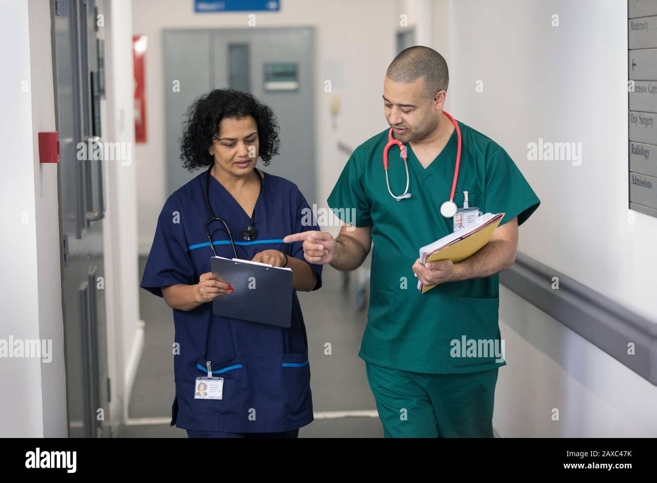 Doctor and surgeon discussing medical chart, making rounds in hospital corridor Stock Photo