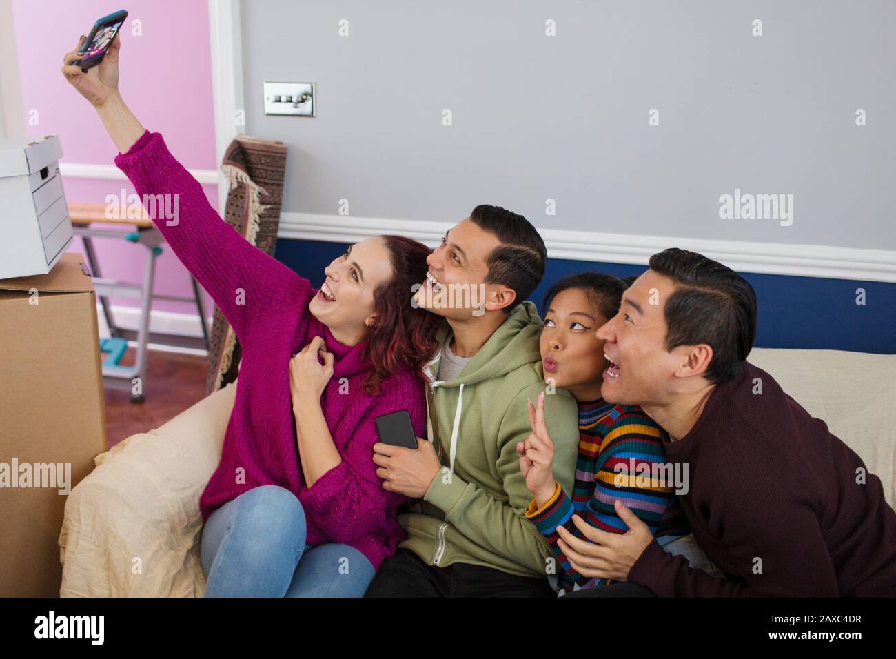 Playful friends taking a break from moving, taking a selfie with smart phone Stock Photo