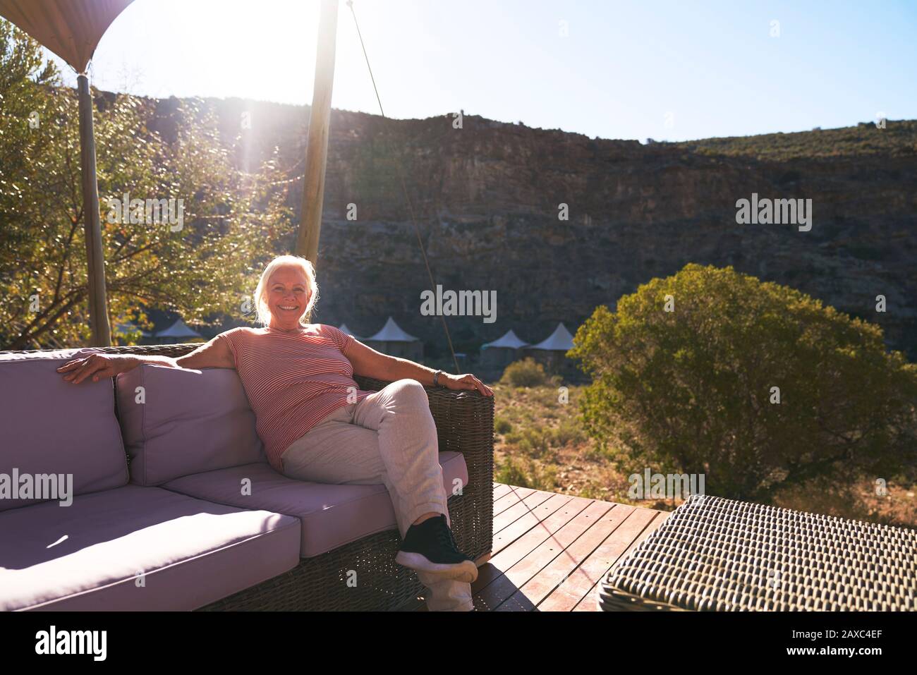 Carefree senior woman relaxing on sunny safari lodge balcony Stock Photo