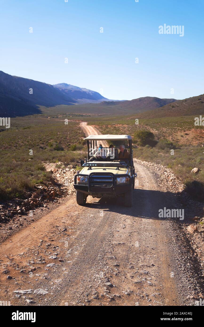 Safari off-road vehicle driving along sunny remote road South Africa Stock Photo