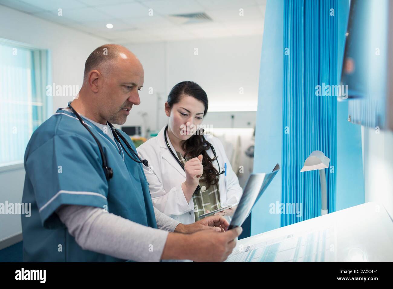 Doctors discussing x-rays in hospital room Stock Photo