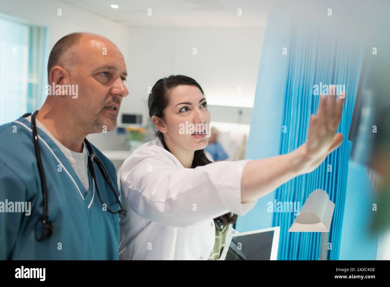Doctors discussing x-rays in hospital room Stock Photo