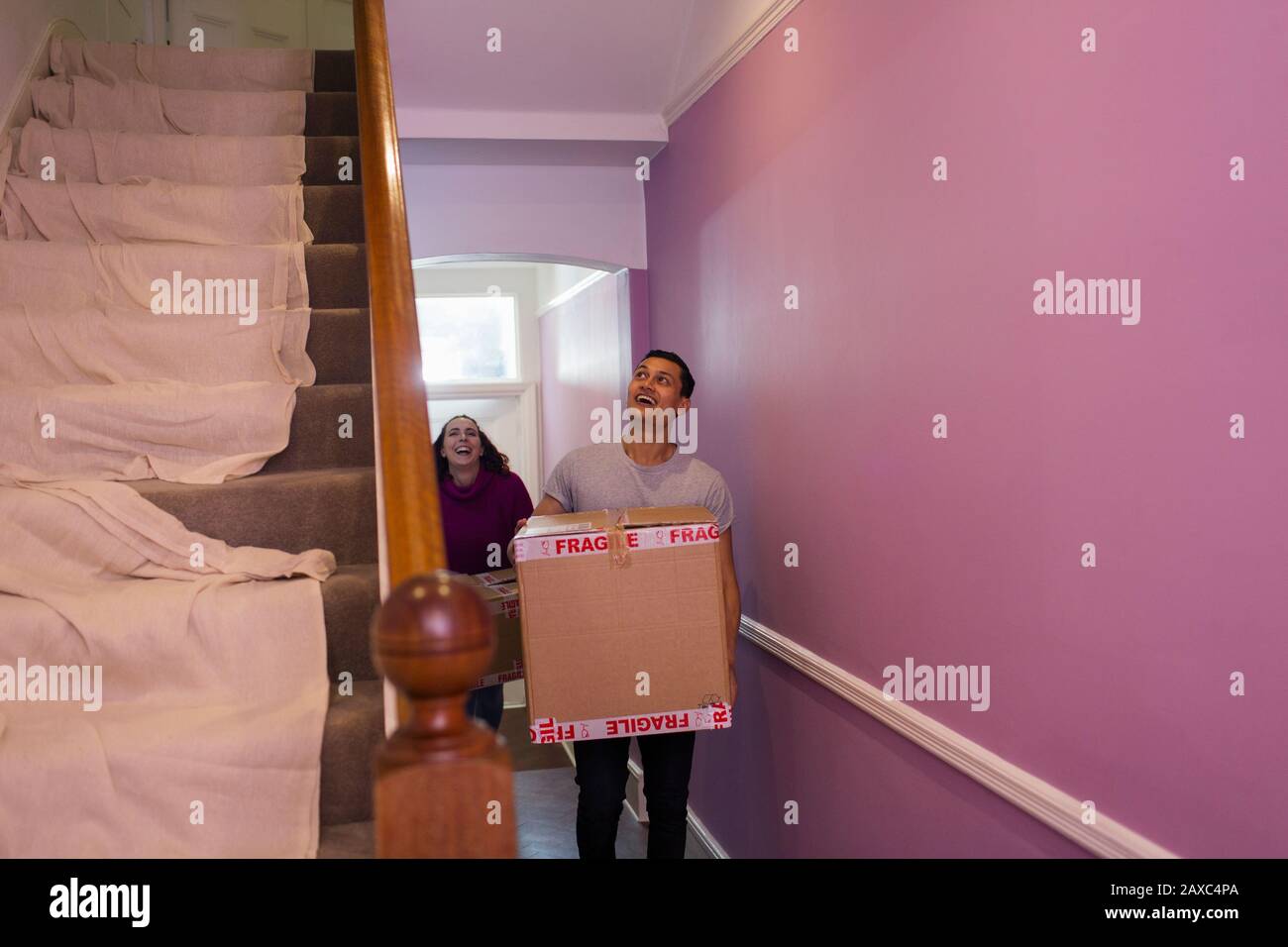 Happy couple moving into new house, carrying cardboard boxes in corridor Stock Photo
