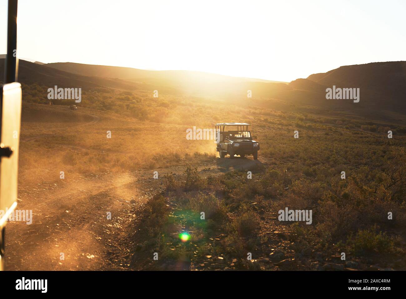 Safari off-road vehicle driving on sunny dirt road South Africa Stock Photo