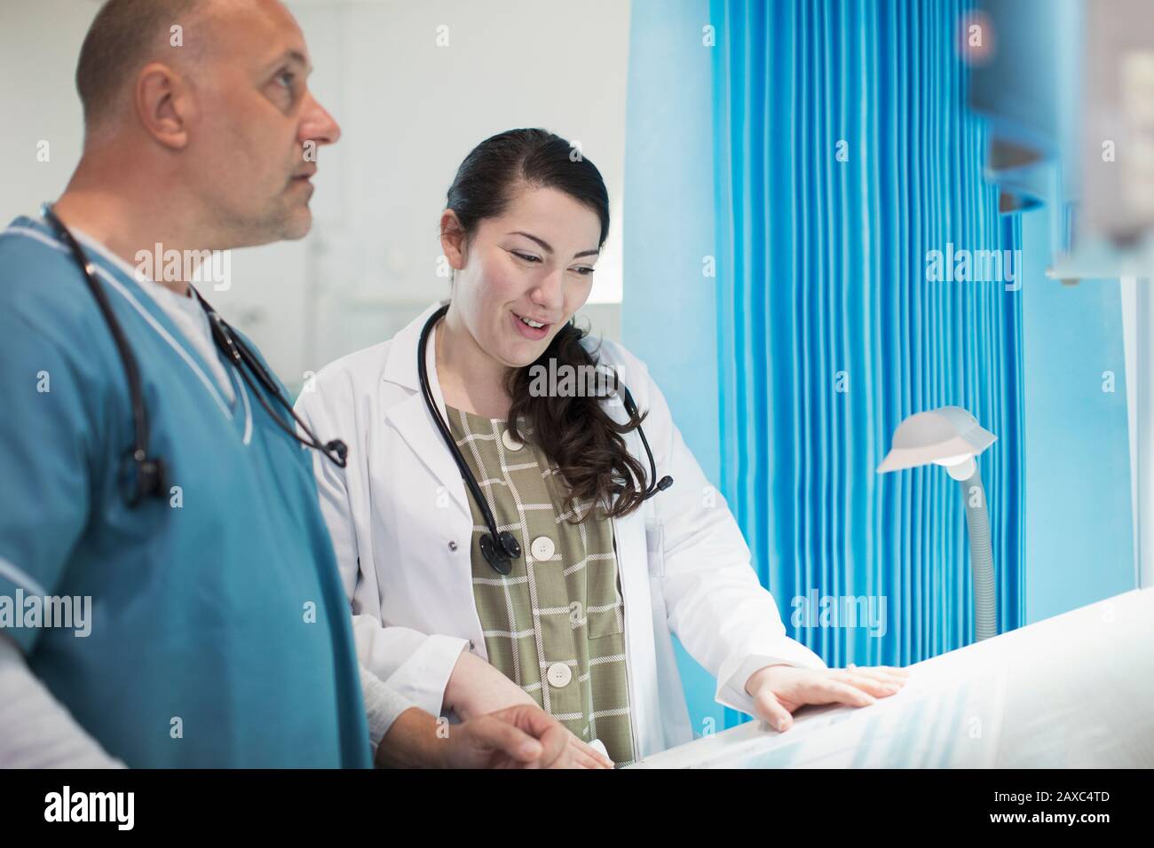 Doctors discussing paperwork in hospital room Stock Photo