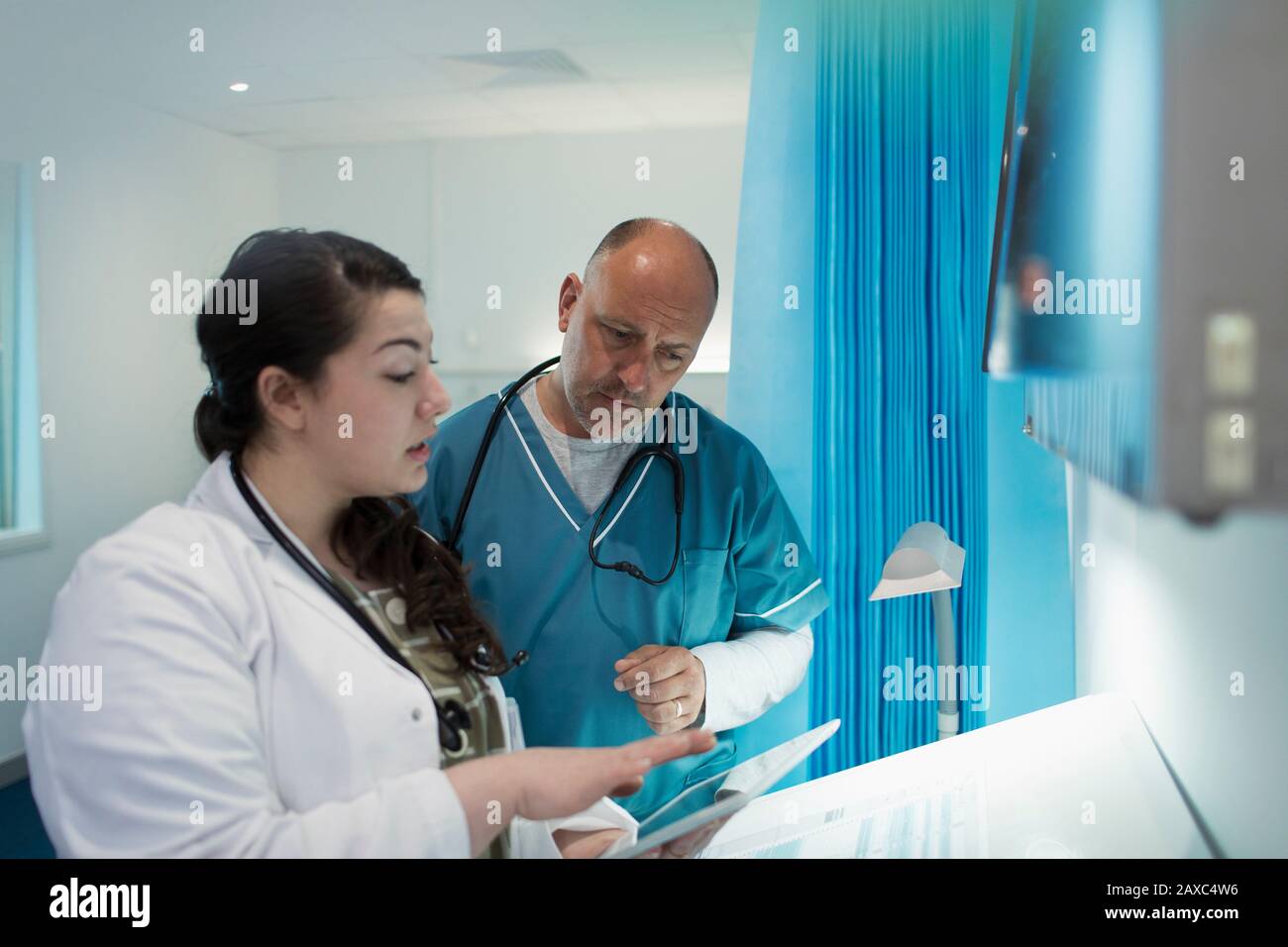 Doctors using digital tablet in hospital room Stock Photo