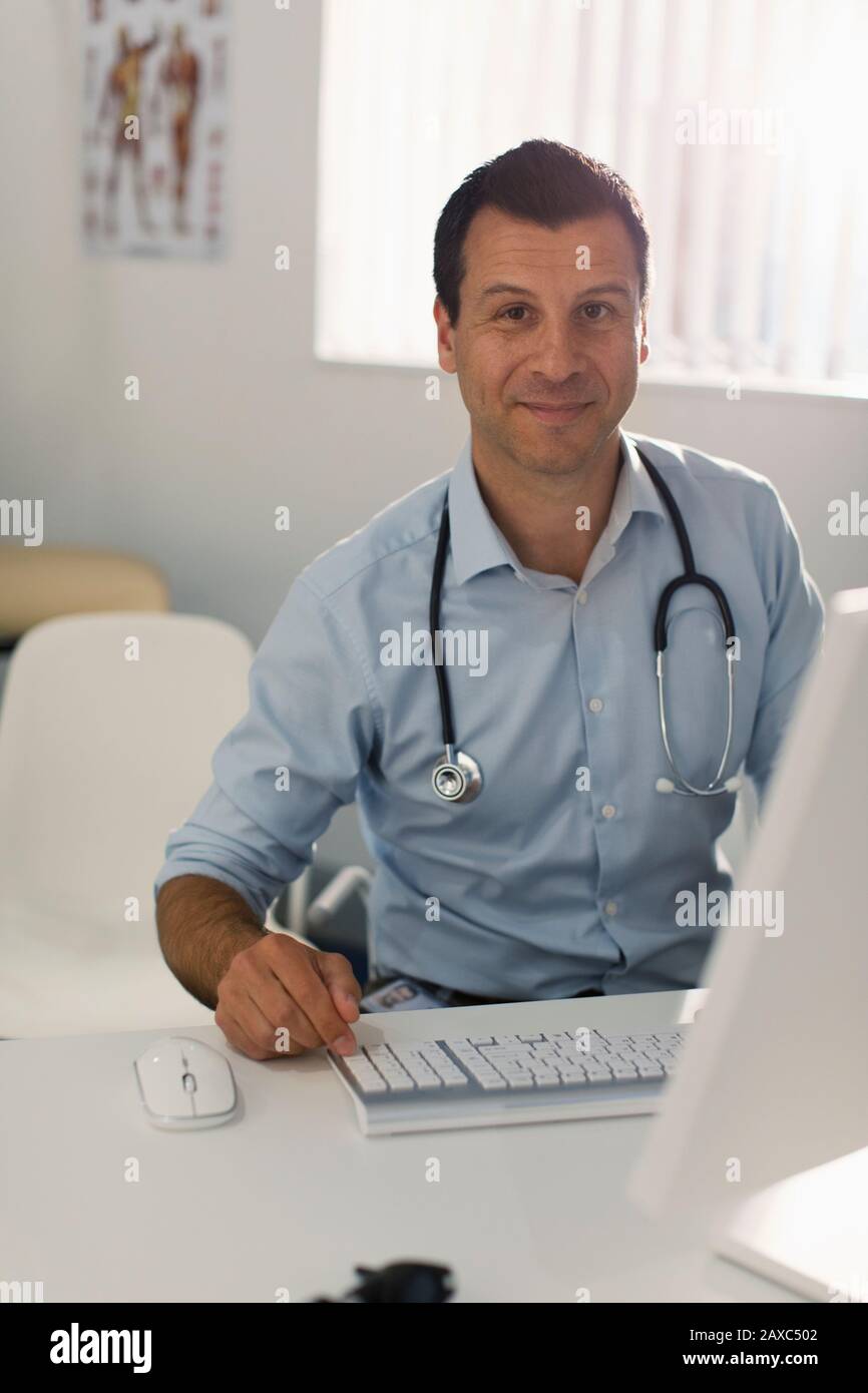 Portrait confident male doctor working at computer in doctors office Stock Photo