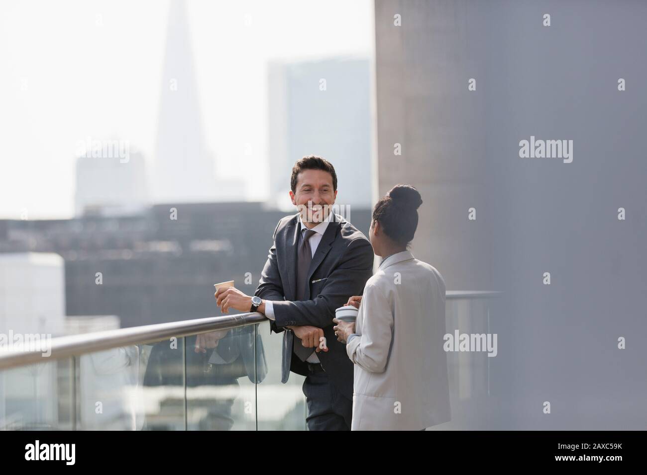 Business people talking and drinking coffee on sunny, urban balcony Stock Photo