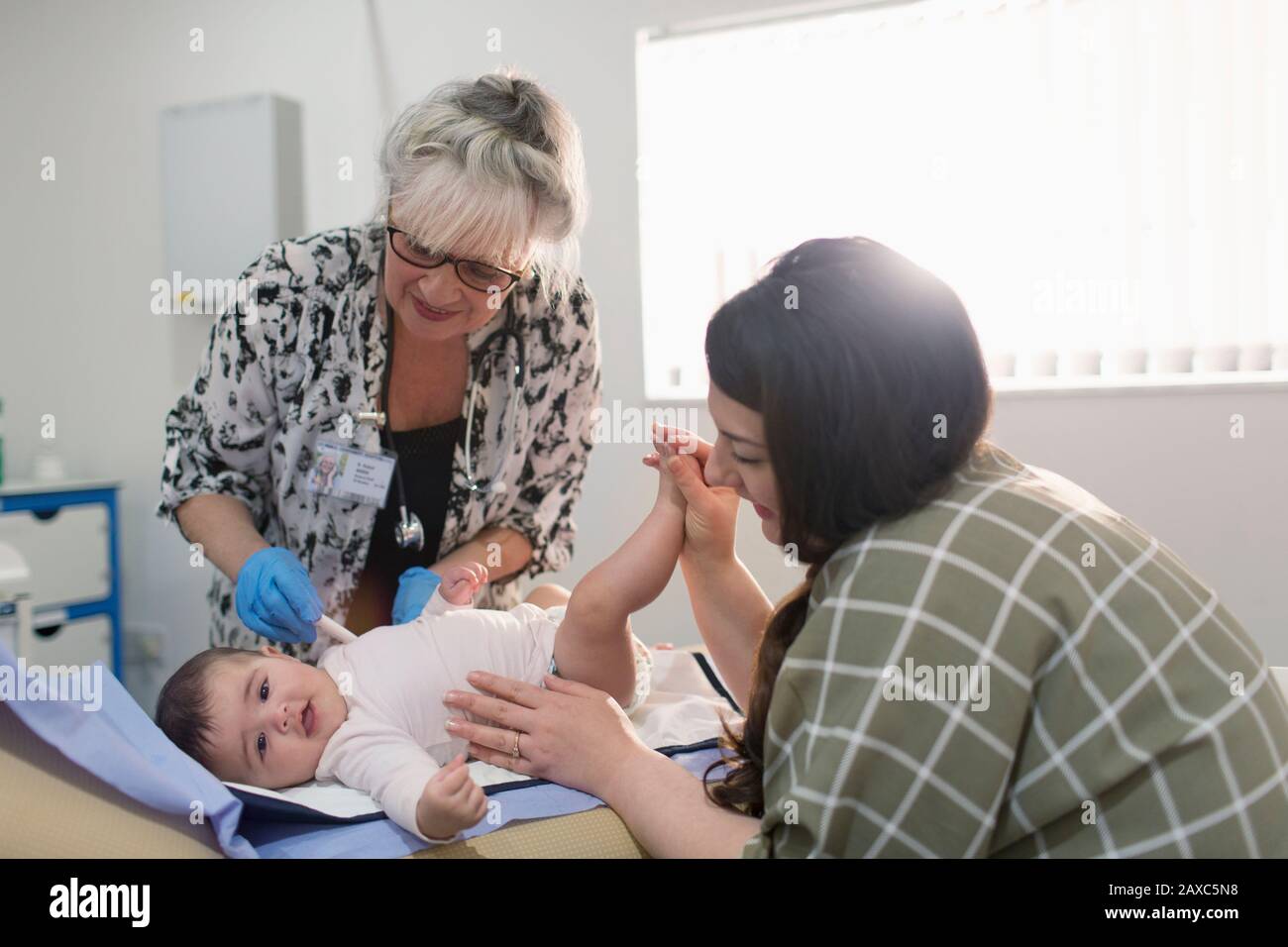 Female pediatrician examining baby girl on examination room table Stock Photo