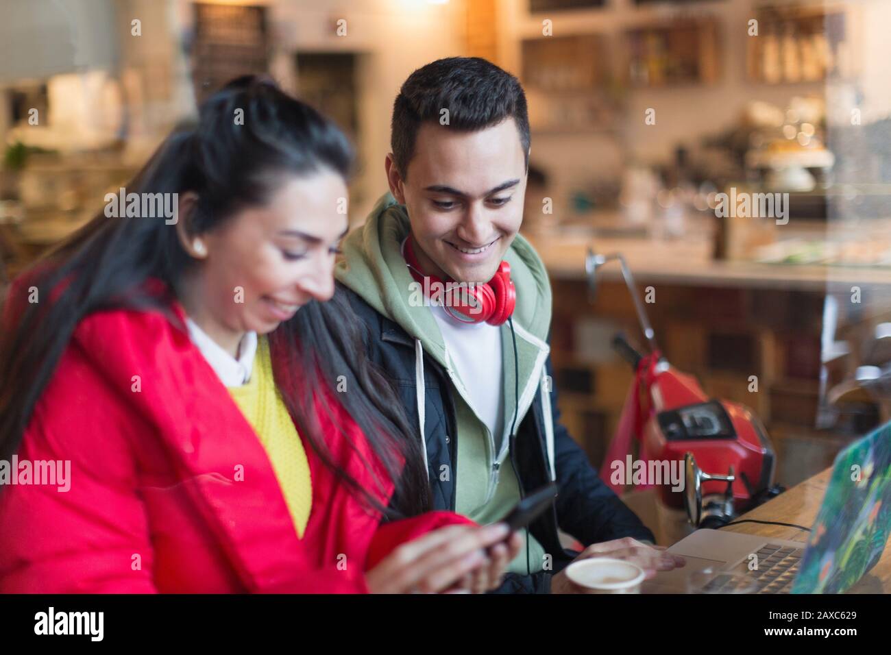 Young couple using smart phone and laptop in cafe Stock Photo