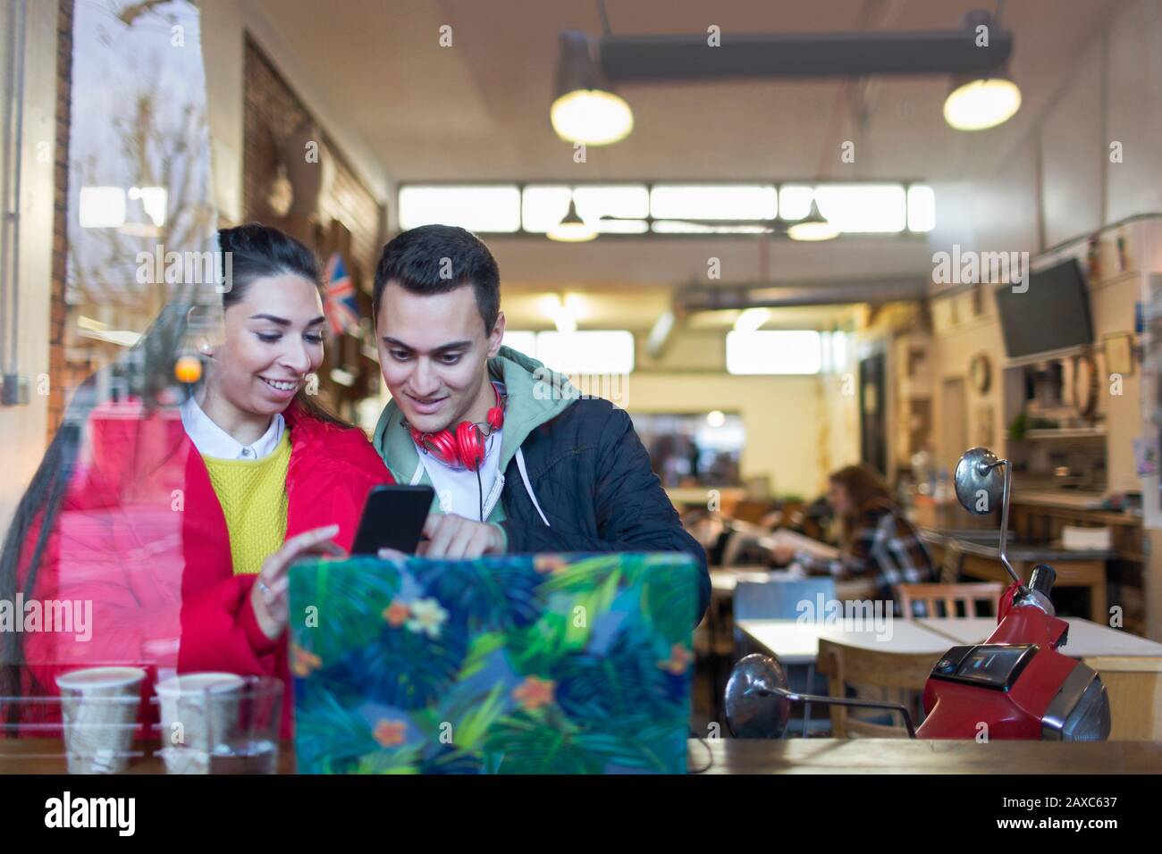 Young couple using smart phone at cafe window Stock Photo