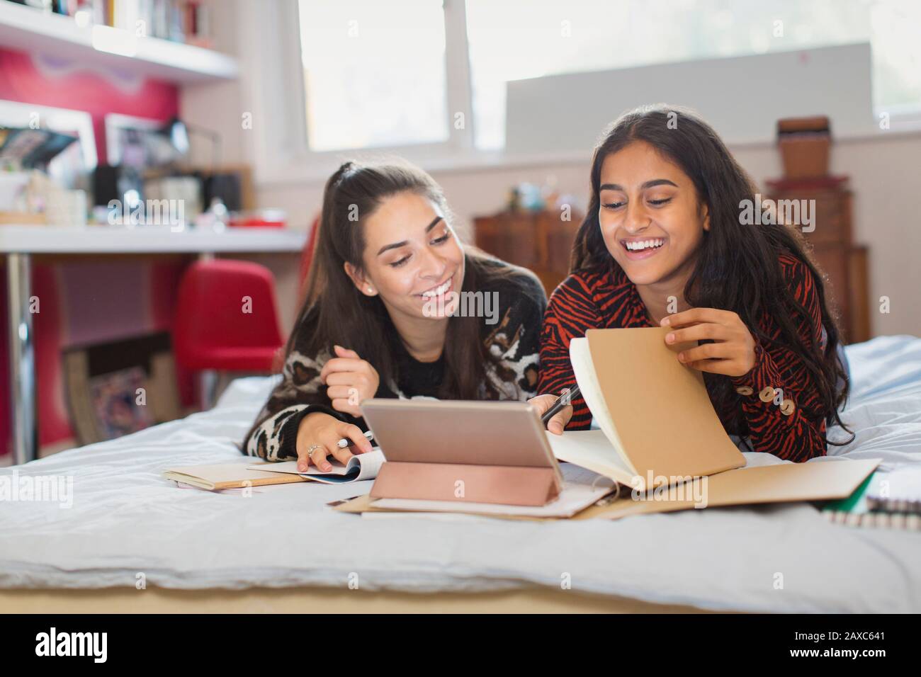 Teenage girl friends studying doing homework on bed Stock Photo