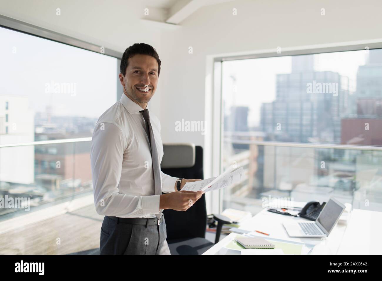 Portrait confident businessman with paperwork in urban office Stock Photo