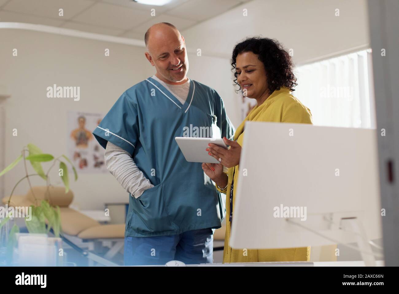 Doctors consulting, using digital tablet in doctors office Stock Photo