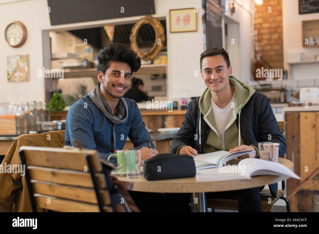 Portrait confident young male college students studying at cafe table Stock Photo