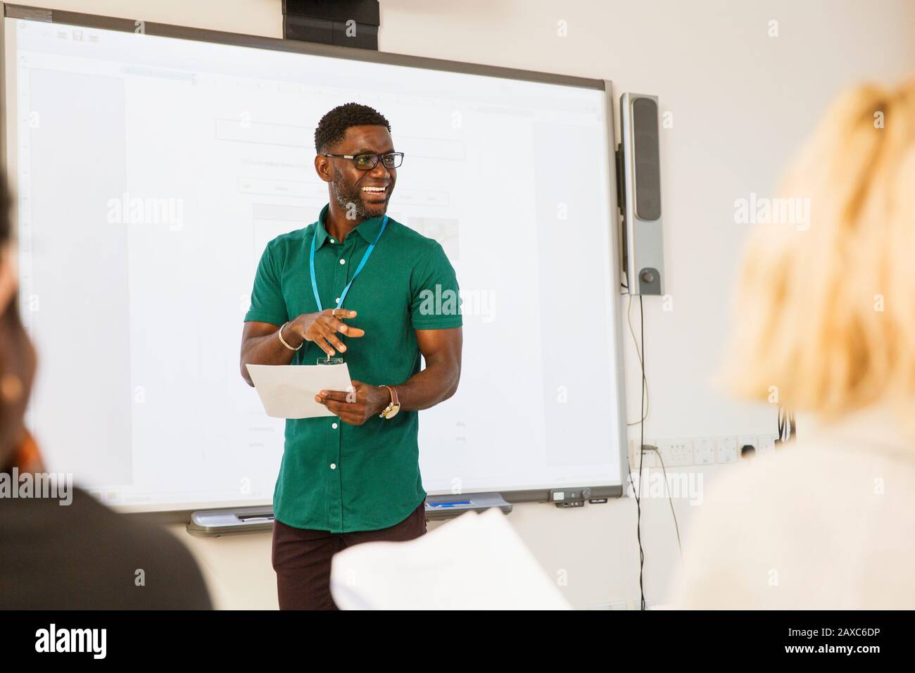 Male community college instructor leading lesson at projection screen ...