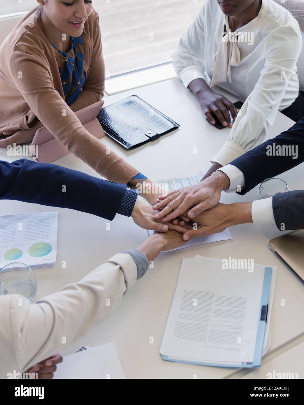 Business people joining hands in conference room meeting Stock Photo