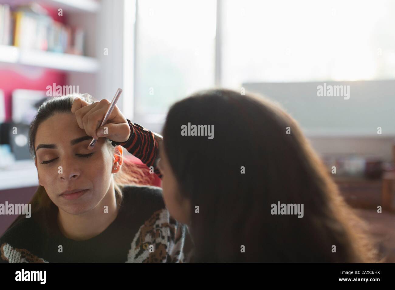 Teenage girl applying eyeshadow makeup to friends eye Stock Photo