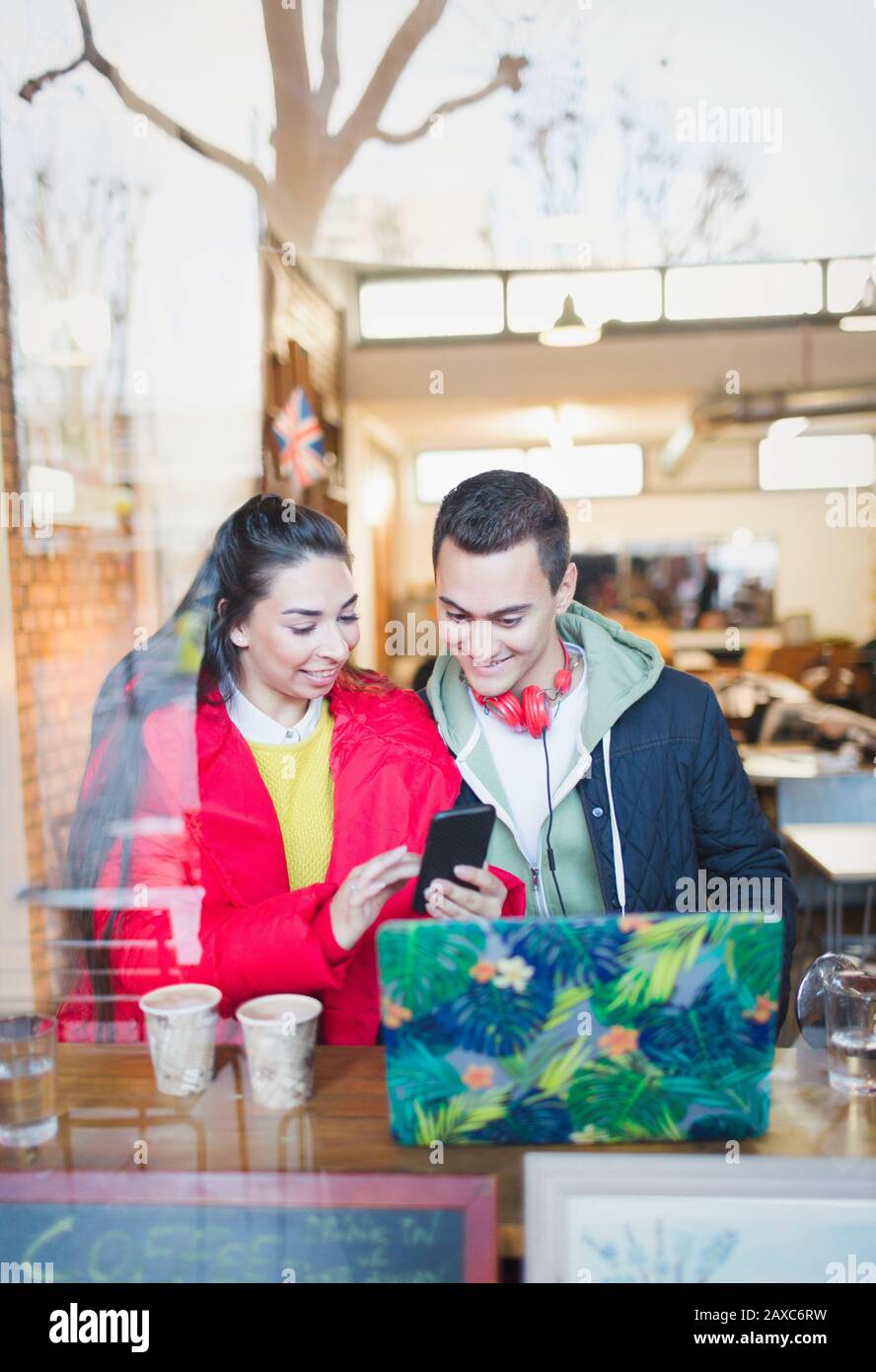 Young couple using smart phone at cafe window Stock Photo