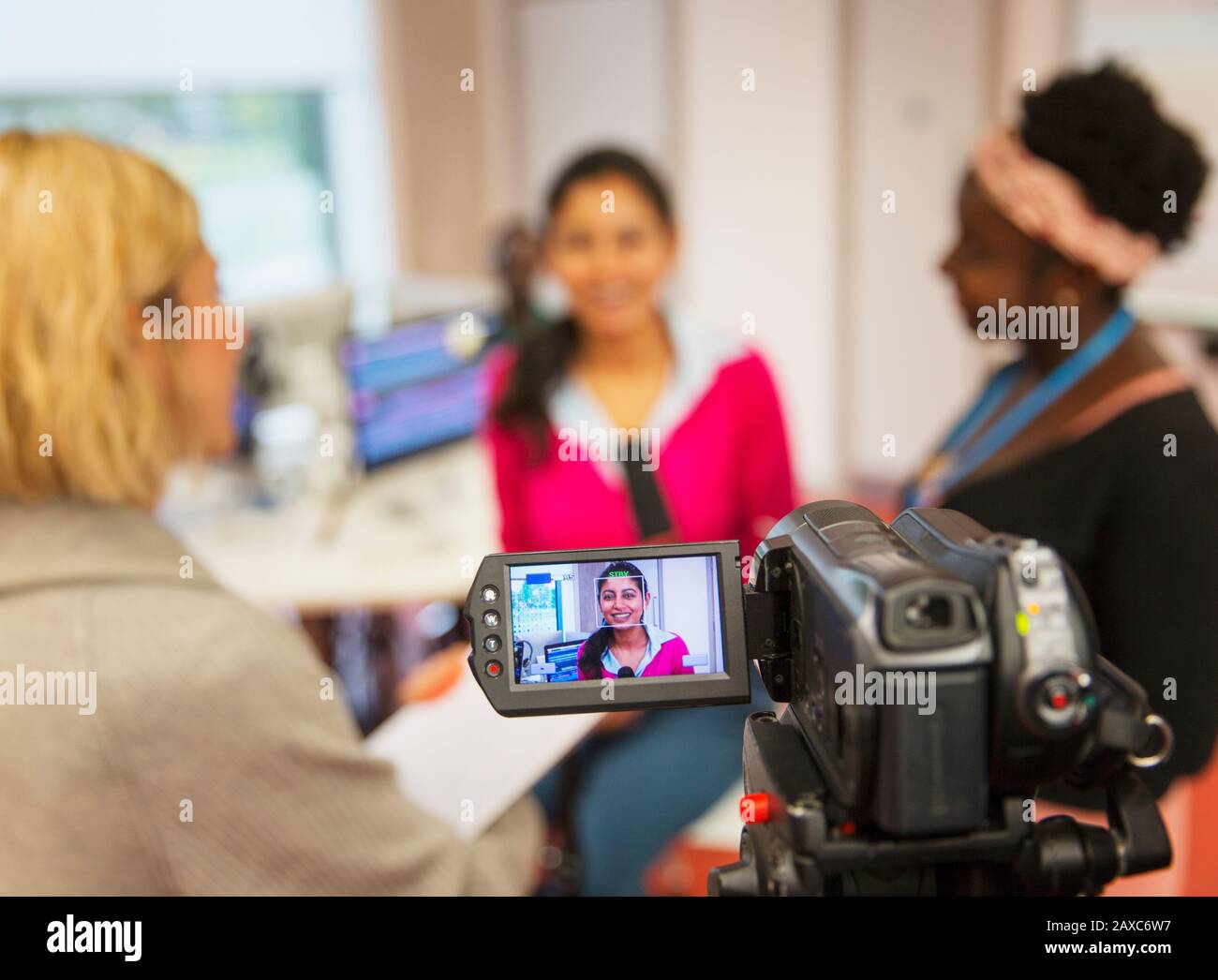 Video camera filming female community college journalism students in classroom Stock Photo