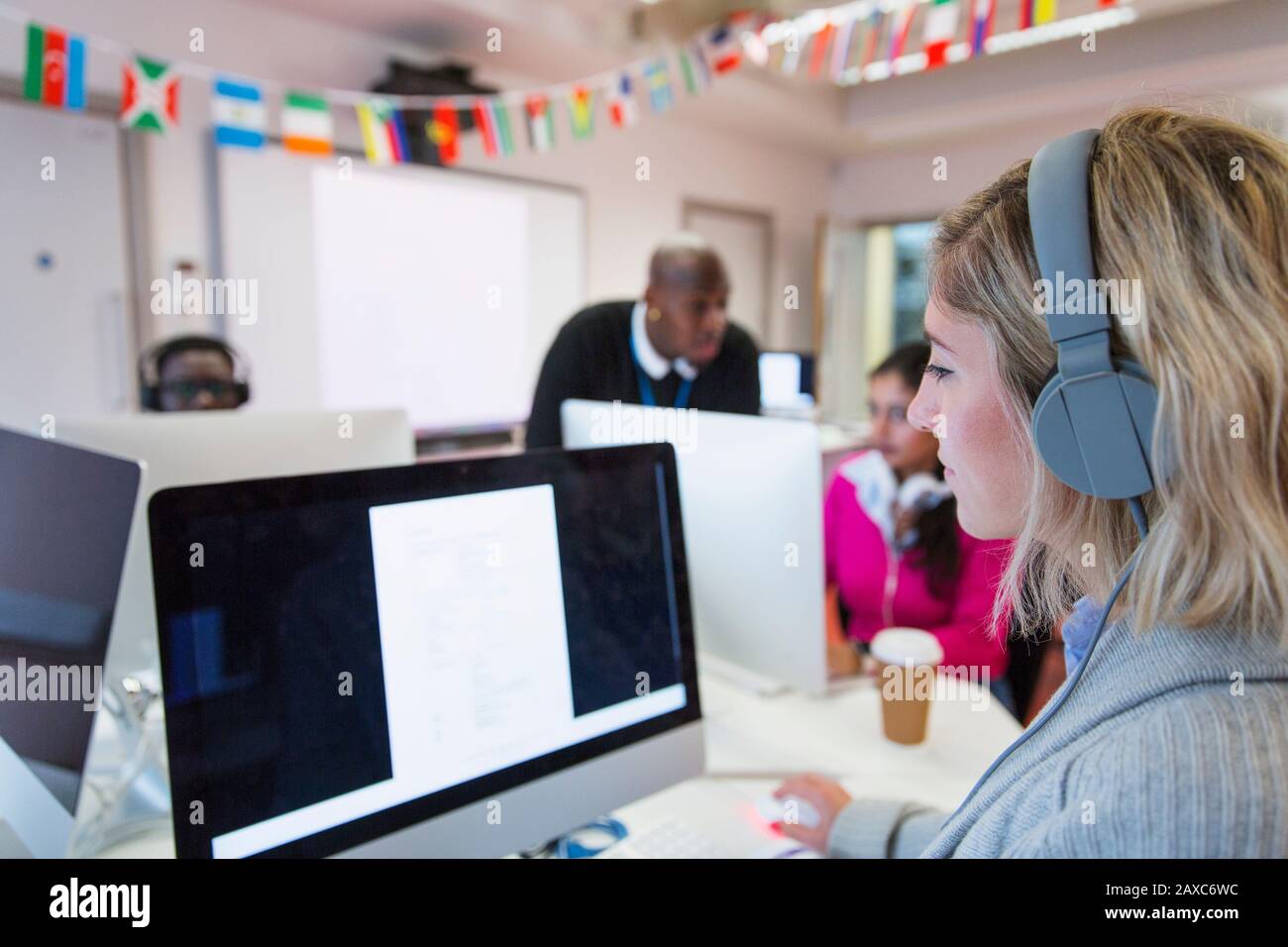 Female community college student with headphones using computer in computer lab classroom Stock Photo