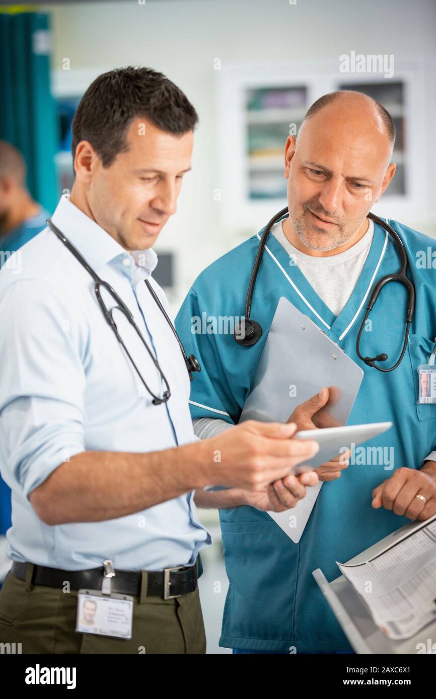 Male doctors consulting, using digital tablet in hospital Stock Photo
