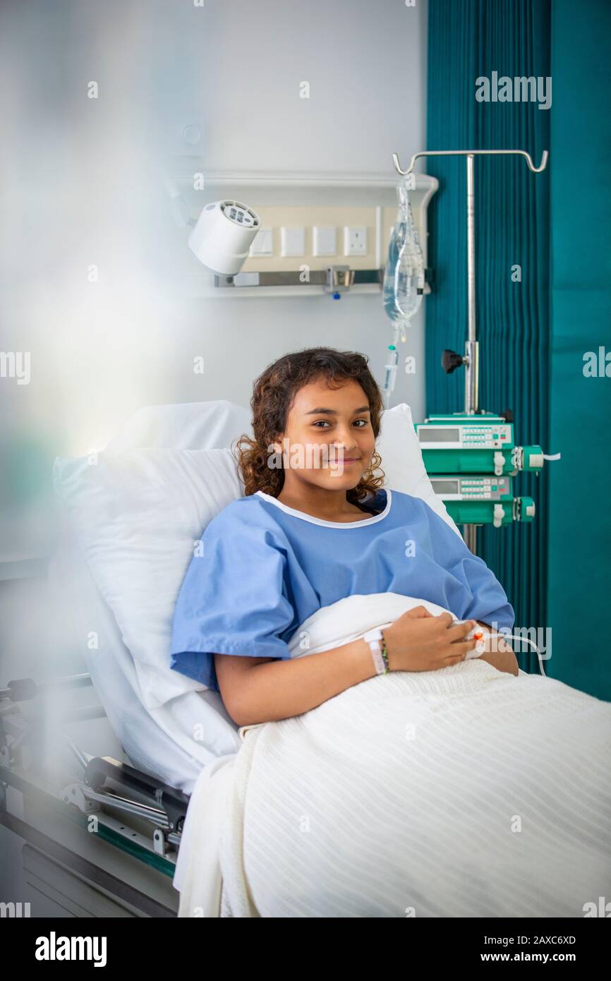 Portrait smiling girl patient in hospital bed Stock Photo