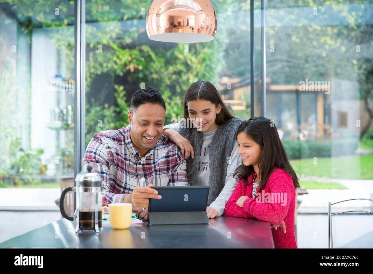 Father and daughters using digital tablet at breakfast table Stock Photo