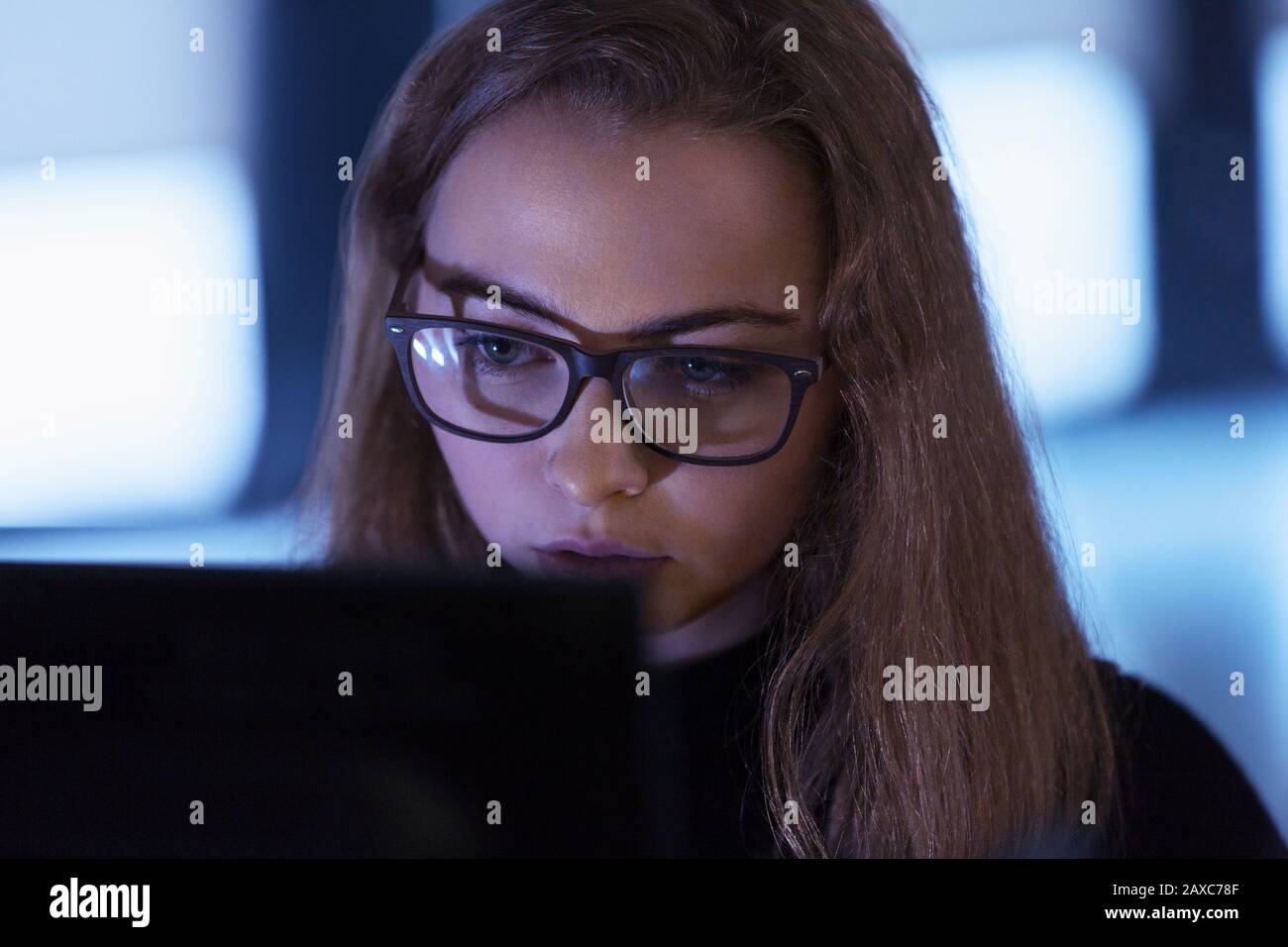 Focused teenage girl in eyeglasses using laptop Stock Photo