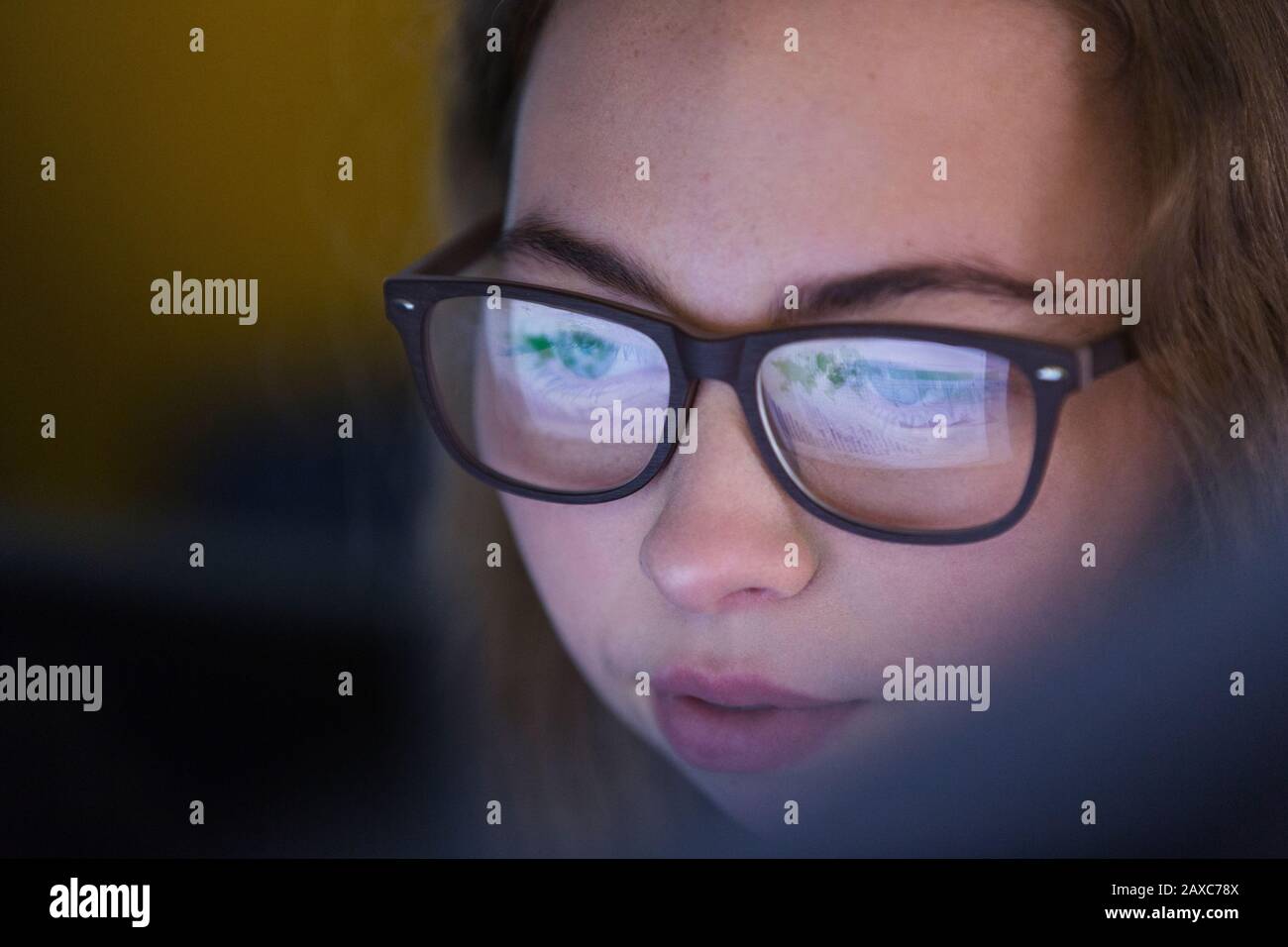 Close up focused teenage girl in eyeglasses looking at device screen Stock Photo