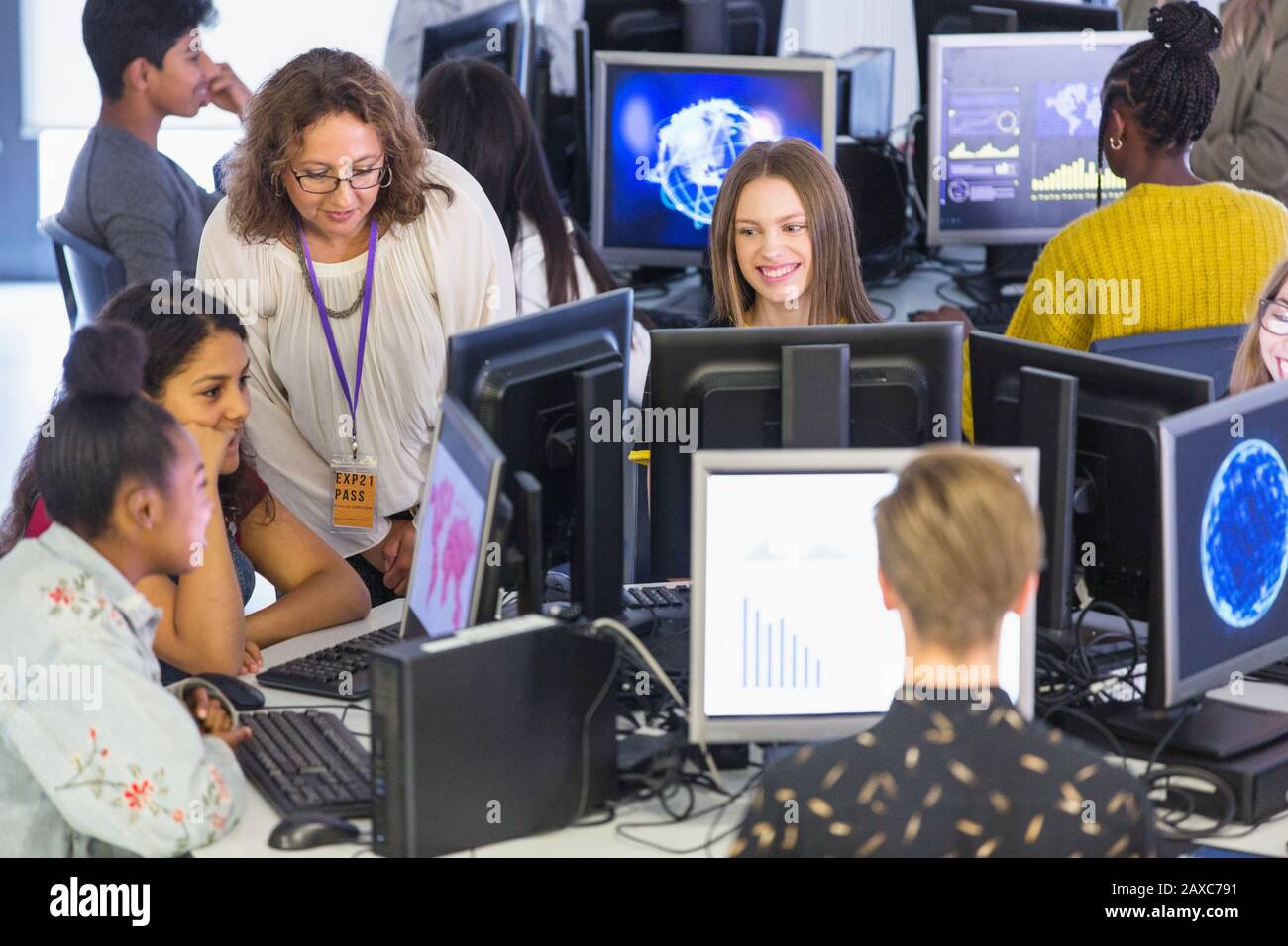 Junior high teacher helping students using computers in computer lab Stock Photo