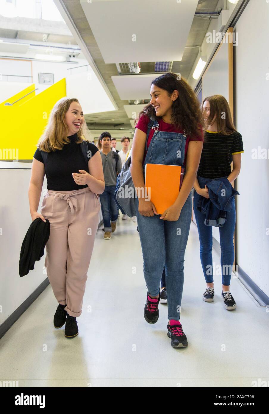 Junior high girl students walking and talking in corridor Stock Photo