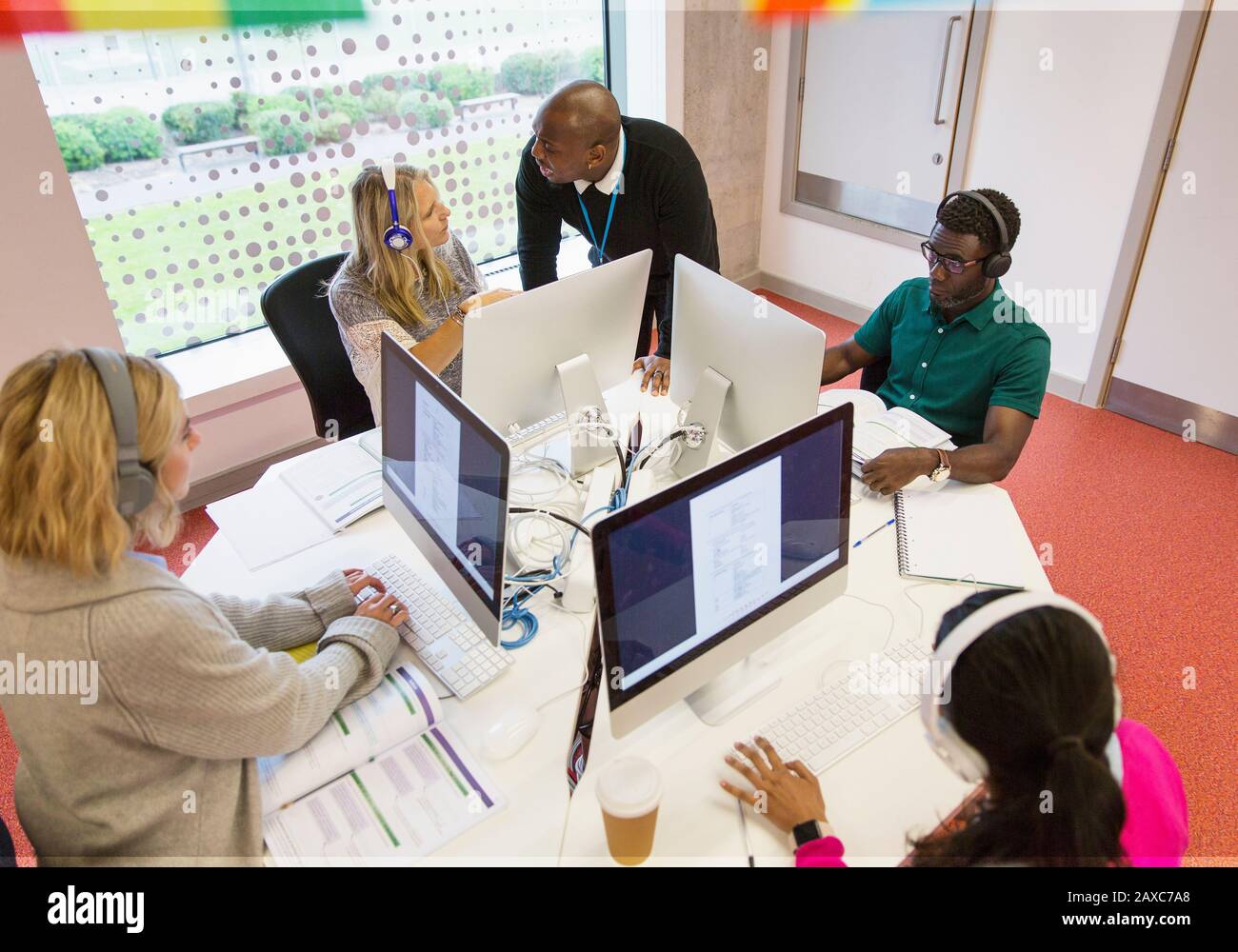 Community college instructor helping students with headphones using ...