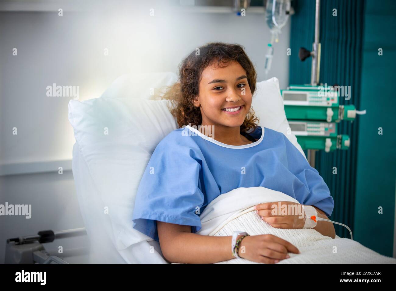 Portrait smiling girl patient in hospital bed Stock Photo