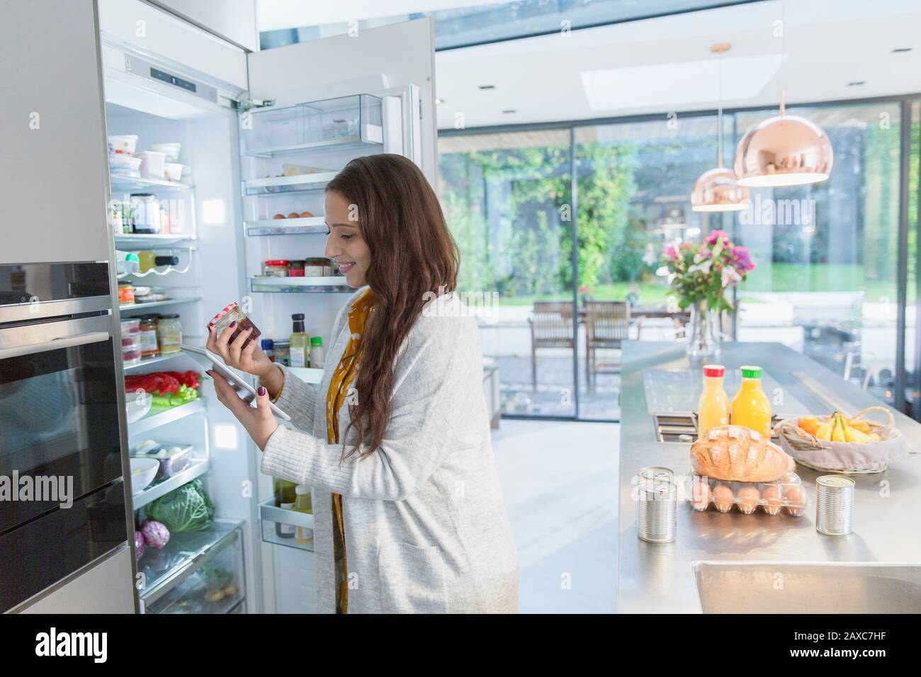 Woman with digital tablet at refrigerator in kitchen Stock Photo
