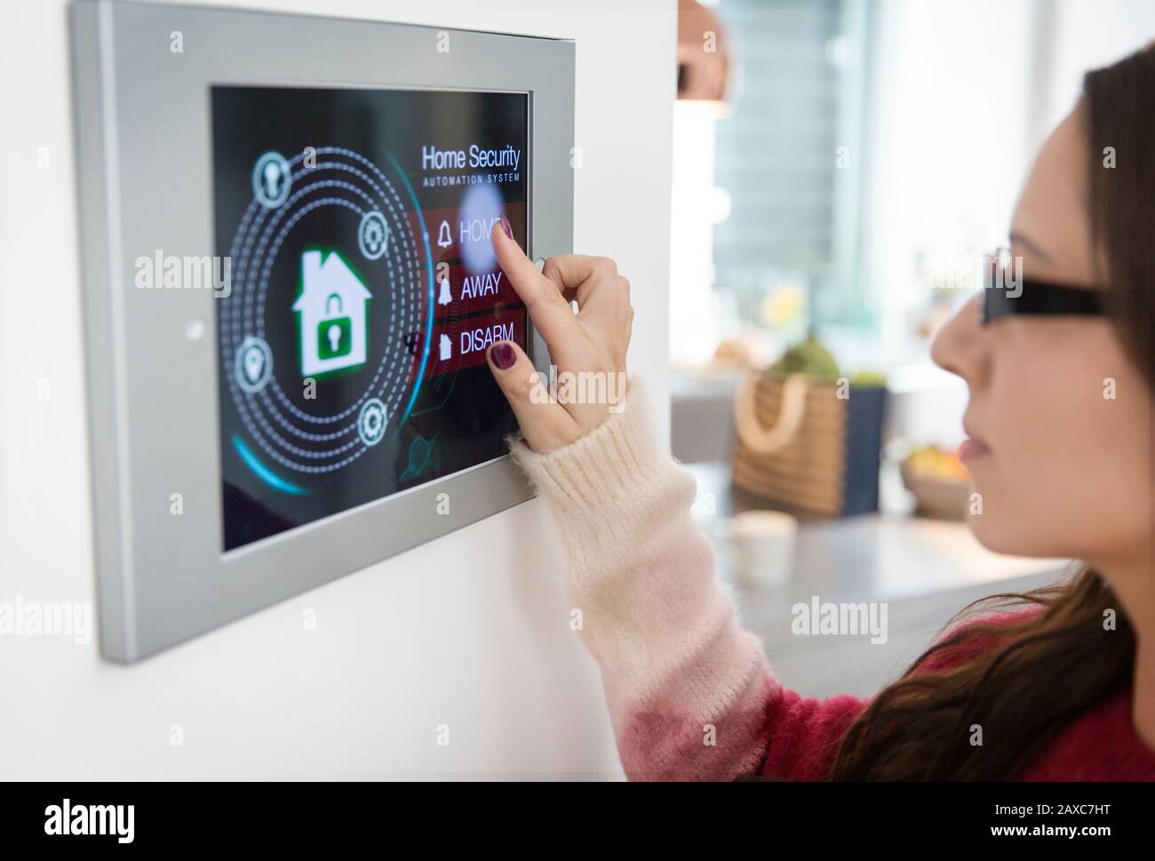 Woman setting touch screen home alarm system Stock Photo