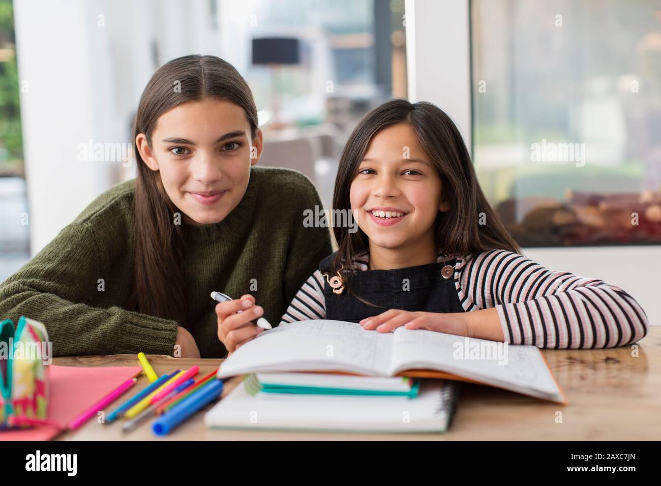 Portrait happy sisters coloring, doing homework Stock Photo