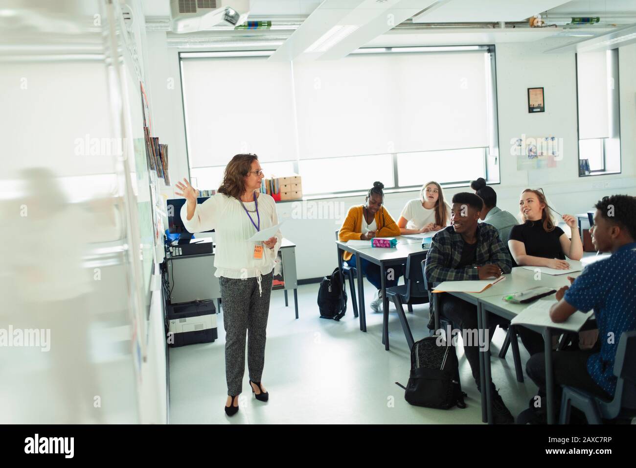 High school students watching teacher leading lesson at whiteboard in classroom Stock Photo