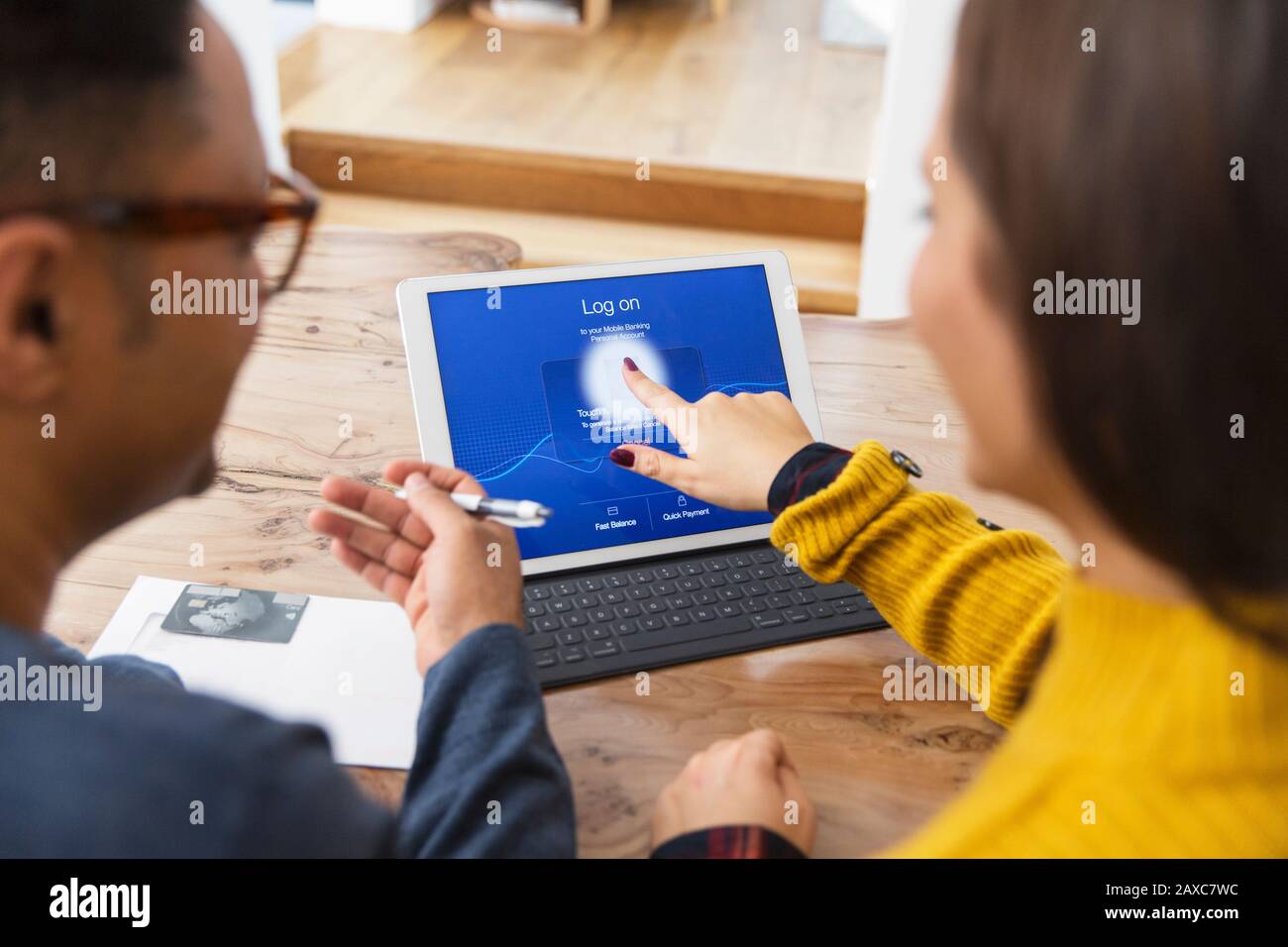 Couple paying bills online, using fingerprint log on at digital tablet Stock Photo
