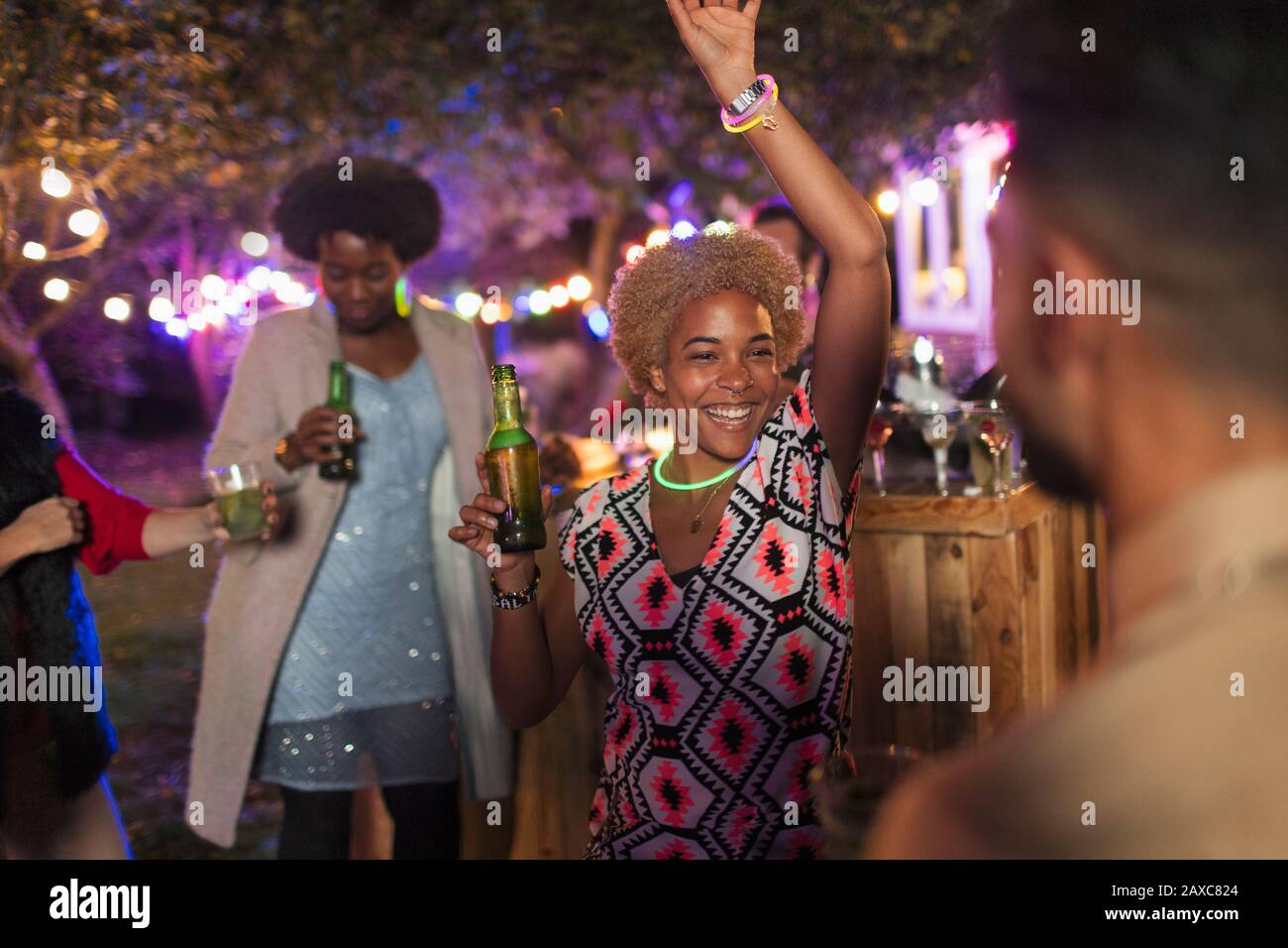 Carefree woman dancing and drinking at garden party Stock Photo