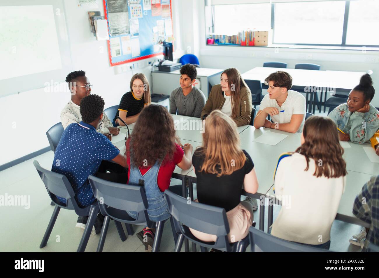 High school students talking in debate class at table in classroom Stock Photo