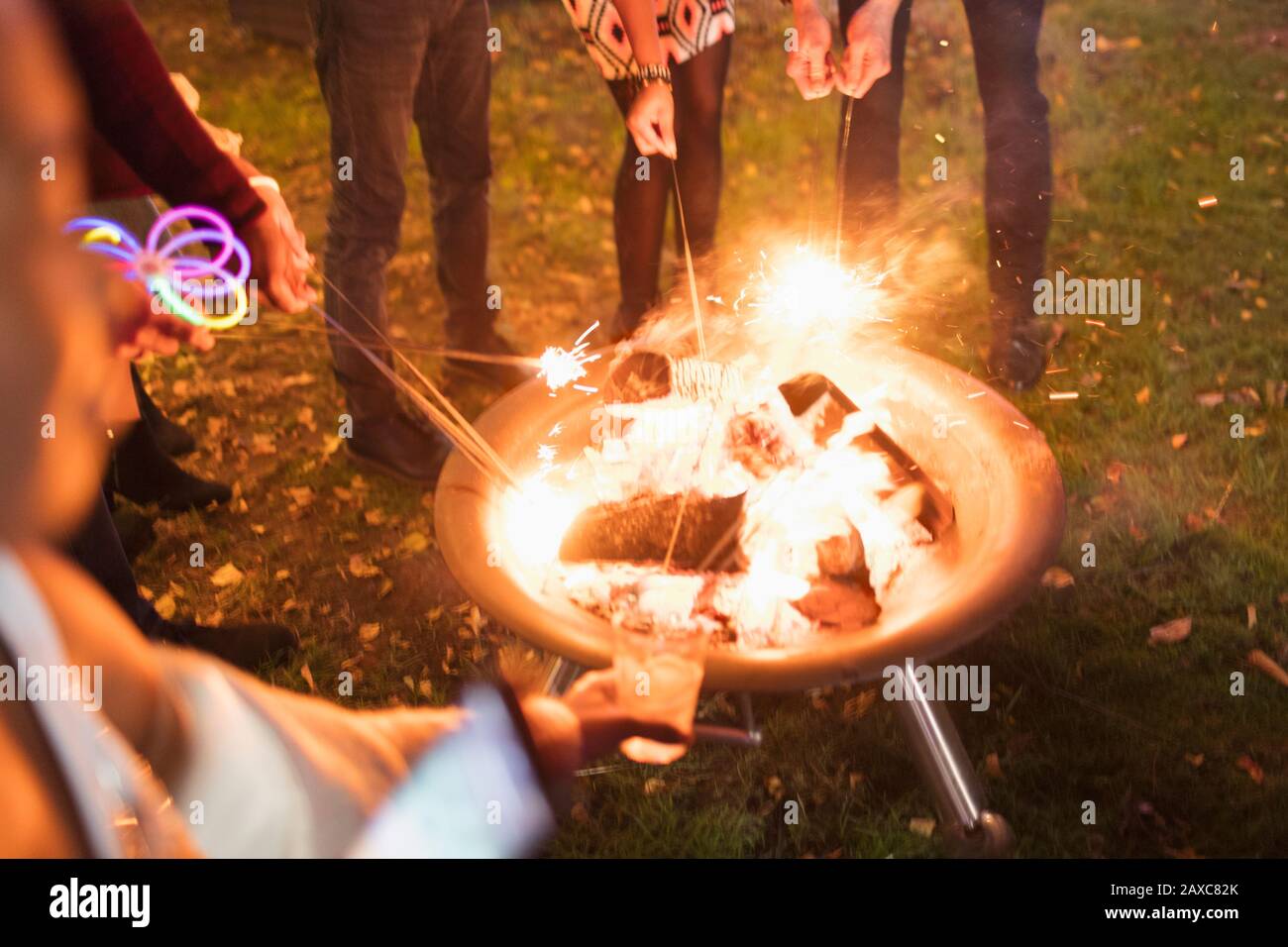 Friends lighting sparklers at fire pit Stock Photo