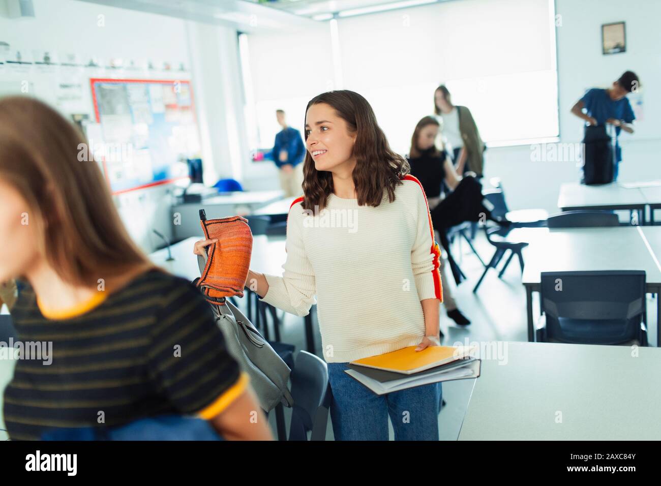Smiling high school girl student leaving classroom Stock Photo