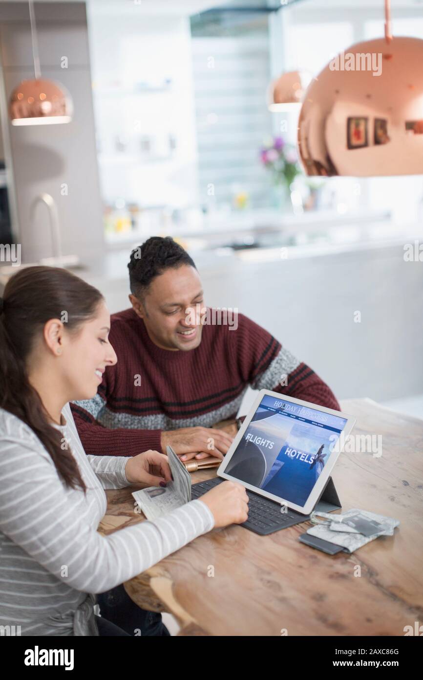 Happy couple planning vacation at digital tablet at dining table Stock Photo