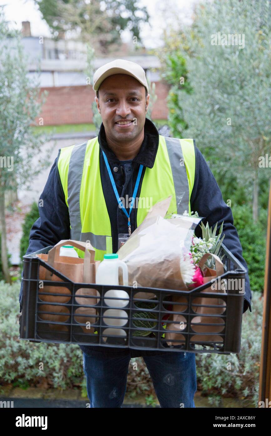 Portrait confident, friendly grocery deliveryman at front stoop Stock Photo